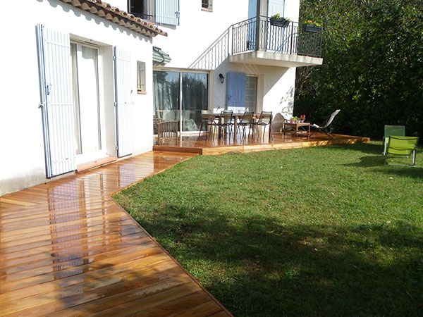 Photographie d'une terrasse en bois avec vernille devant une maison blanche pour la pose de terrasses en bois à Nice